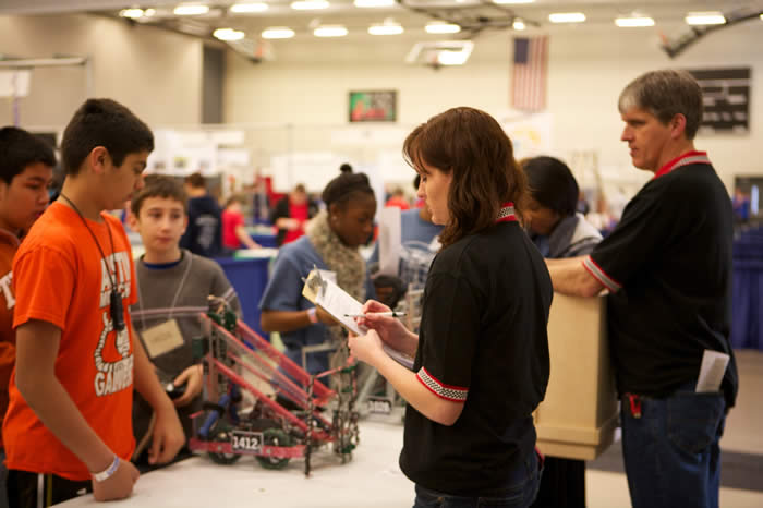 Volunteer supporting students at a robotics event